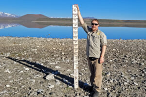 Leonardo Buria, the National Parks Northern Patagonia Regional Director of Conservation, holds up a ruler that in 2007 was completely covered by water in Laguna Blanca National Park. Credit: Facundo Scordo