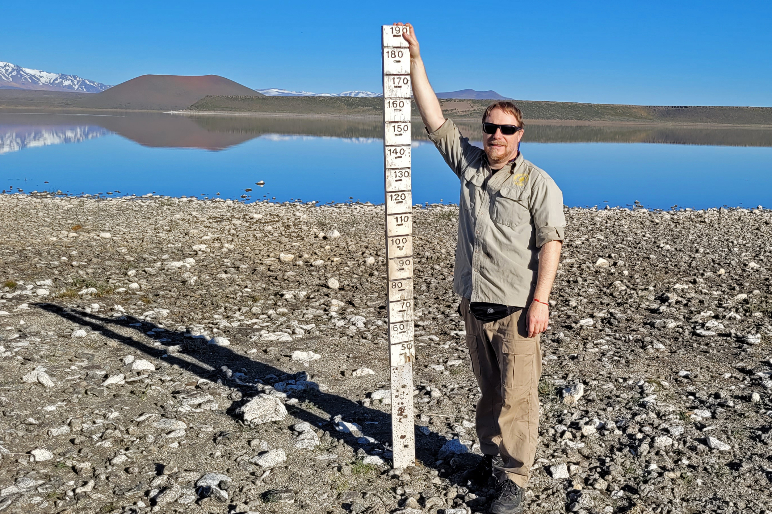 Leonardo Buria, the National Parks Northern Patagonia Regional Director of Conservation, holds up a ruler that in 2007 was completely covered by water in Laguna Blanca National Park. Credit: Facundo Scordo