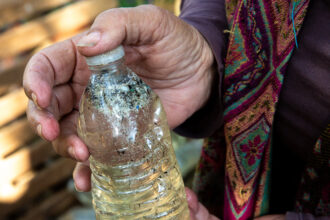 Diane Wilson holds a bottle with PVC plastic powder, a type of microplastic, collected in the Matagorda Bay system in December 2024. Credit: Dylan Baddour/Inside Climate News
