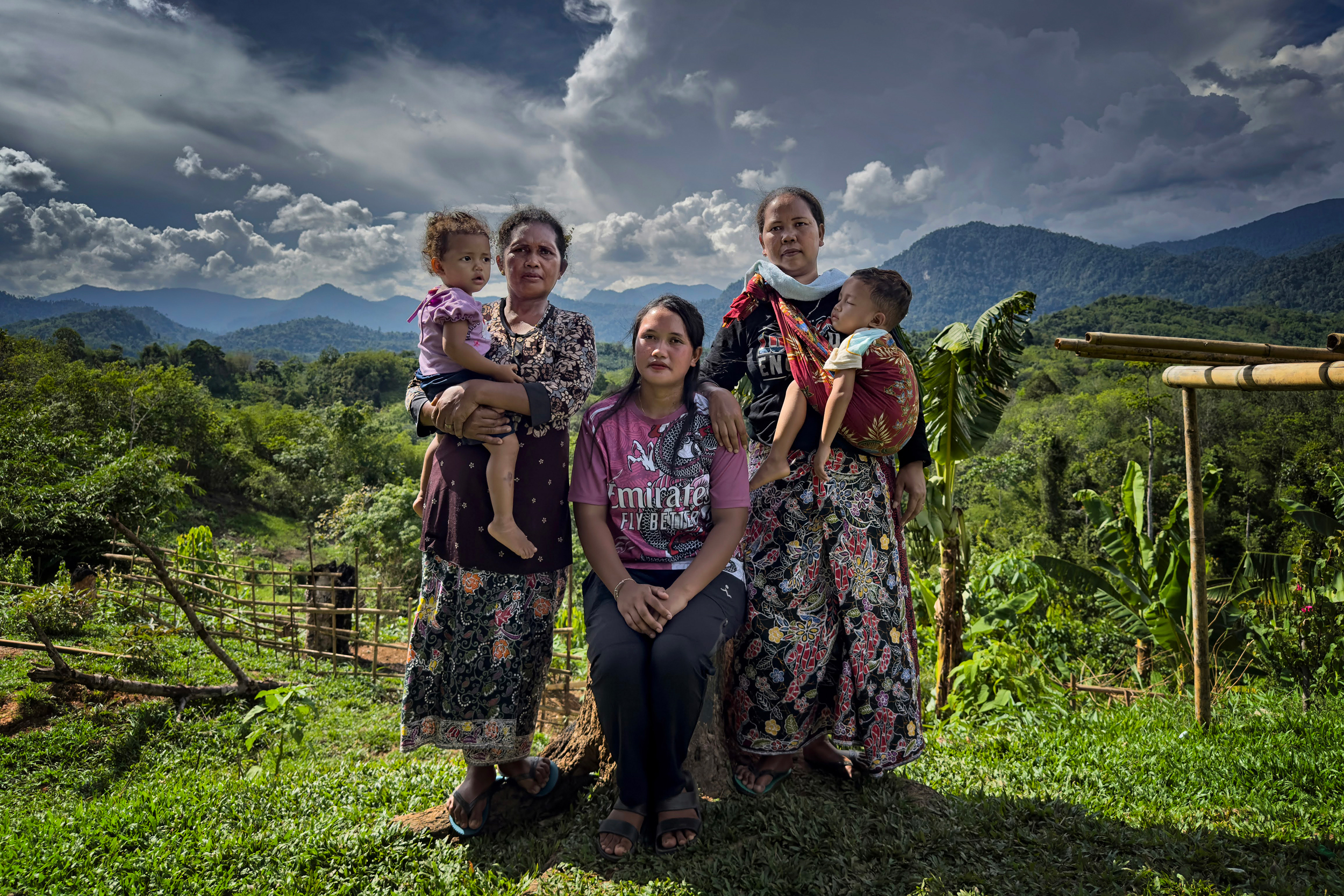 Syahira binti Hamid (center), Pisie Amud’s widow, sits with her mother Sharifan binti Semen (right) and mother-in-law, Junaida binti Acan, while they hold her children in the Indigenous Temiar settlement of Pos Pasik.