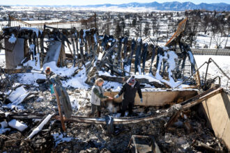 A family walks through what remains of their grandfather’s house in a neighborhood decimated by the Marshall Fire on Jan. 2, 2022, in Louisville, Colo. Credit: Michael Ciaglo/Getty Images