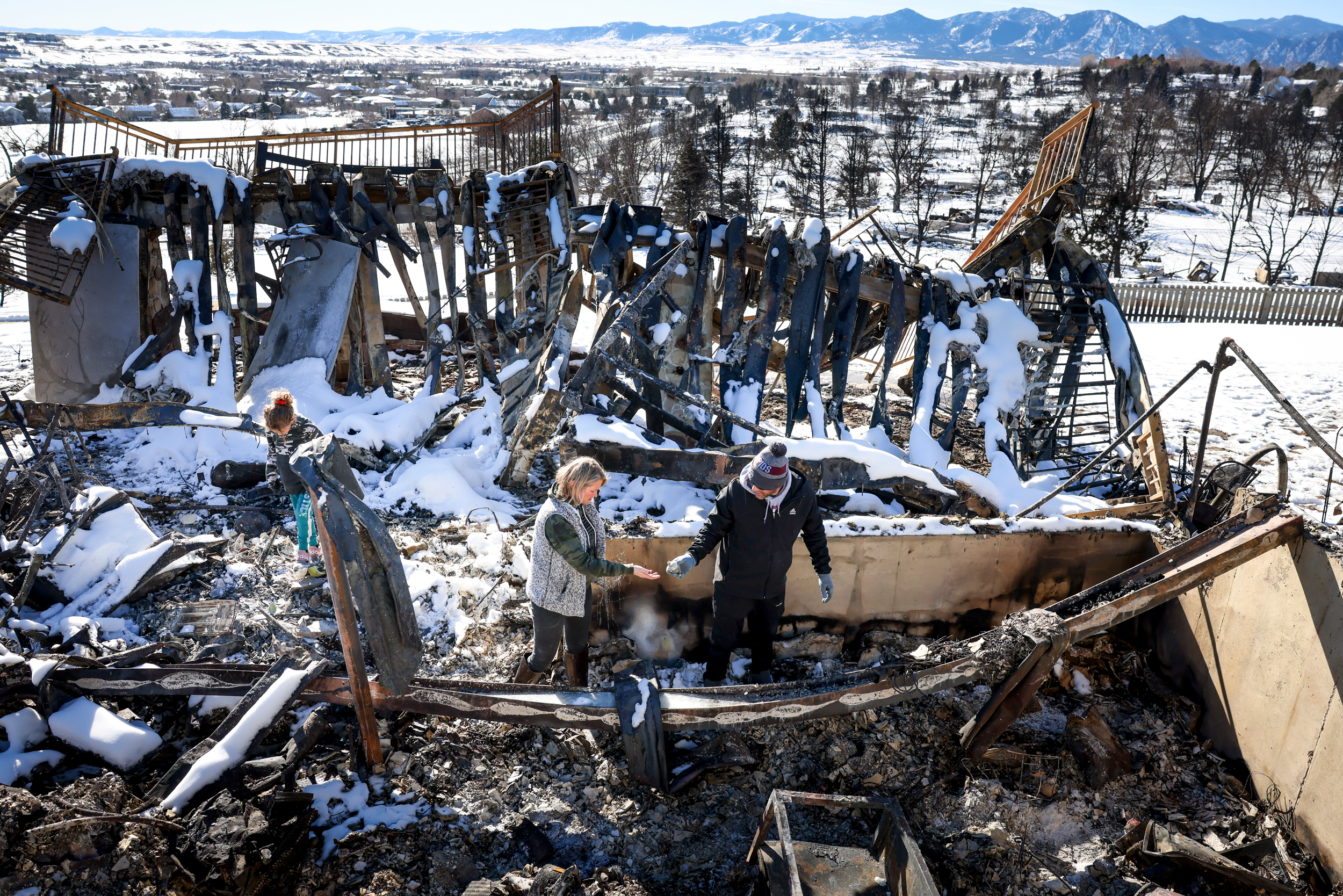 A family walks through what remains of their grandfather’s house in a neighborhood decimated by the Marshall Fire on Jan. 2, 2022, in Louisville, Colo. Credit: Michael Ciaglo/Getty Images