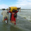 People carry their belongings through a flooded area after heavy monsoon rainfall in Punjab, Pakistan on Aug. 25, 2022. Credit: Shahid Saeed Mirza/AFP via Getty Images