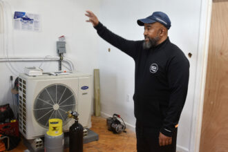 Jackie Robinson, lead instructor at the Energy Coordinating Agency, shows off a heat pump in his Philadelphia laboratory on April 22. Robinson and other instructors prepare hundreds of students each year for careers in HVAC and energy efficiency. Credit: Kyle Bagenstose/Inside Climate News