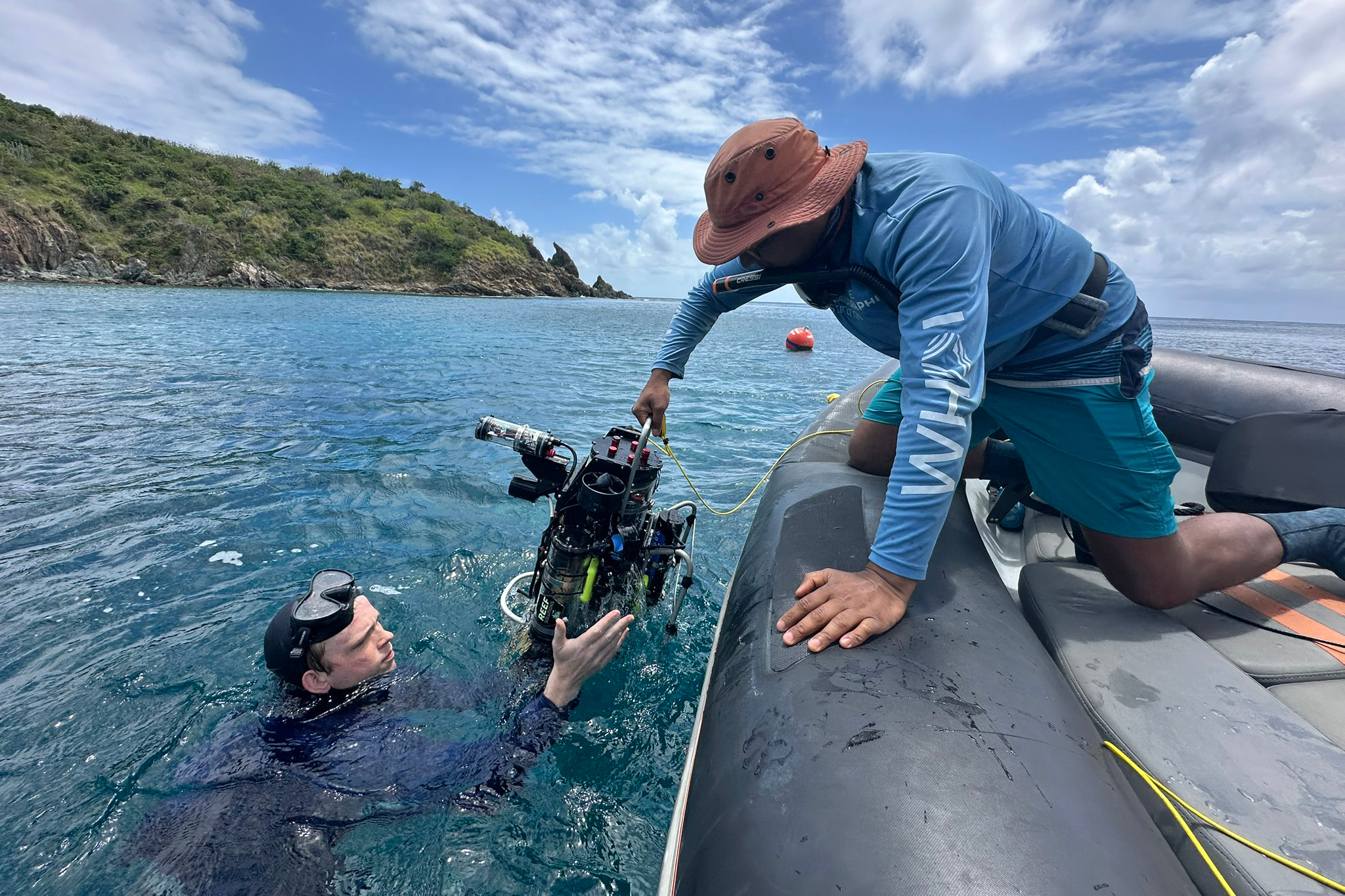 Yogesh Girdhar hands CUREE to a team member to test out its ability to map and monitor a coral reef at a popular snorkeling spot called Tektite in St. John. Credit: Teresa Tomassoni/Inside Climate News