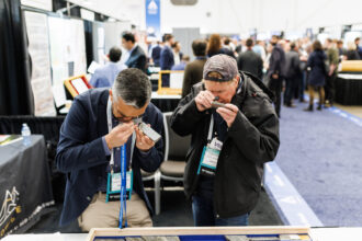 Participants at the Association for Mineral Exploration conference in Vancouver in January examine core samples through magnifying devices. The yearly conference is known as a gathering place for companies with prospects in Alaska. Credit: Jesse Winter for Northern Journal and Inside Climate News