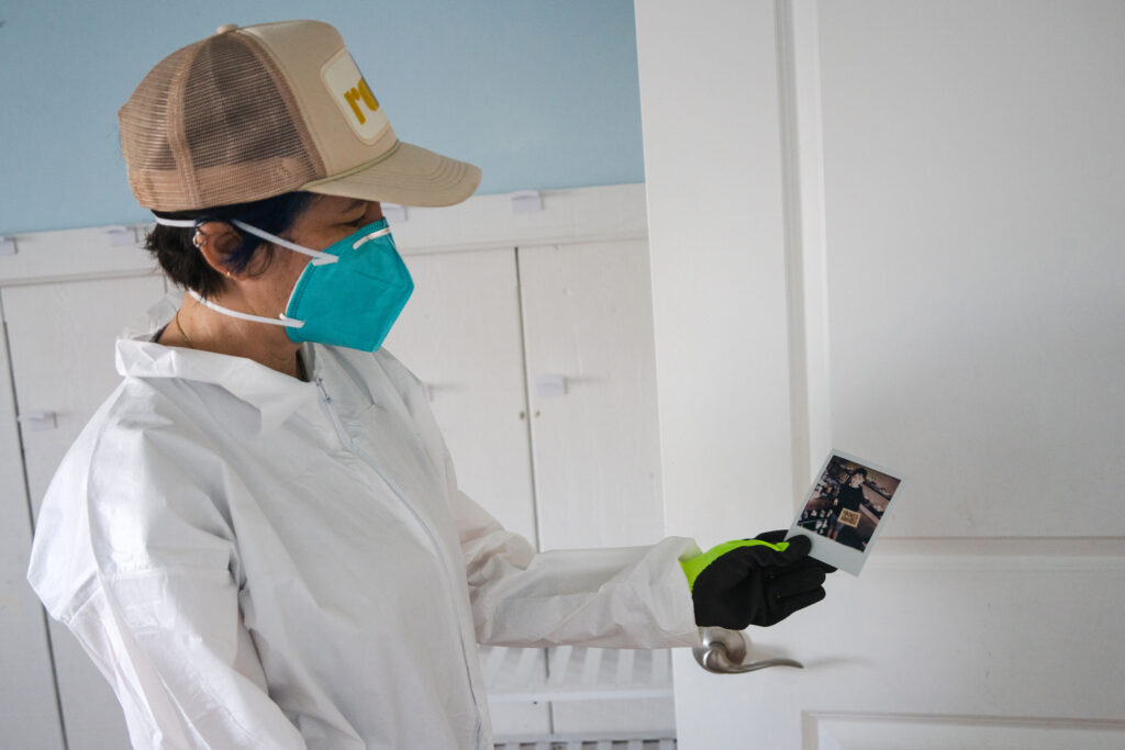 Winter Reign, covered in PPE, holds up a picture of her son, Leaf, from a few years ago.
