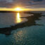 The image shows the sun near the horizon, reflecting off the water