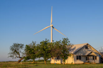 A wind turbine sits behind a house in Nolan, Texas. Credit: Brandon Bell/Getty Images