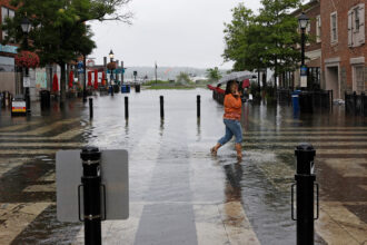 A woman walks through high tide floodwaters on Aug. 9, 2024, in Alexandria, Va. Credit: Anna Moneymaker/Getty Images