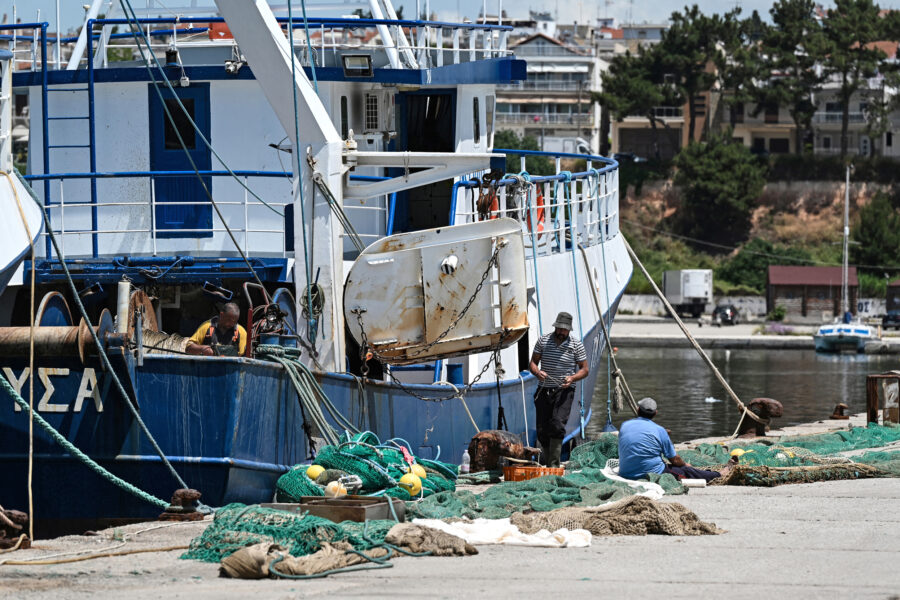 Workers handle a fishing net next to a commercial trawler docked at the port of Nea Michaniona in northern Greece on May 22. Credit: Sakis Mitrolidis/AFP via Getty Images
