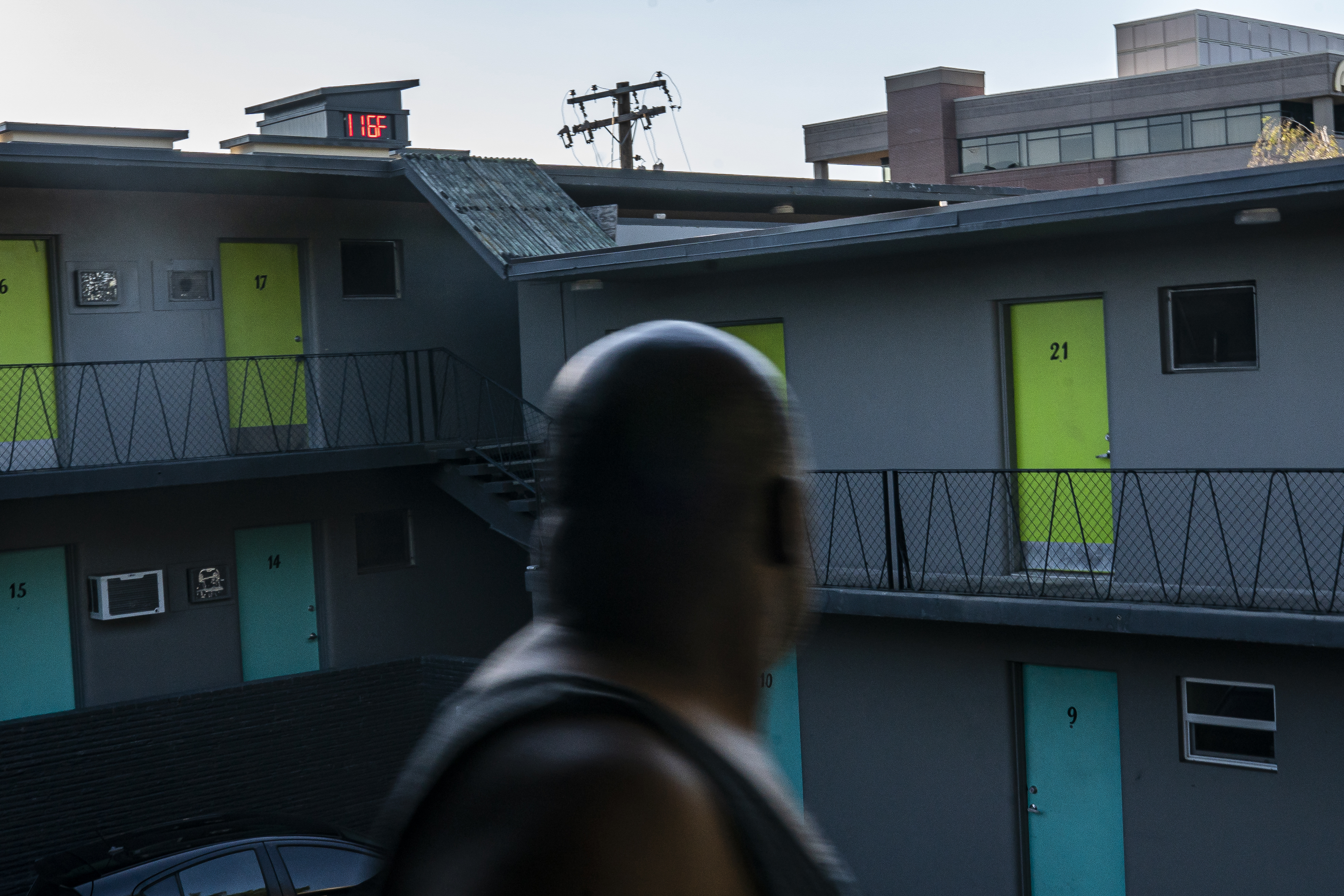 In Vancouver, Washington, Everett Clayton looks at a digital thermometer on a nearby building that reads 116 degrees while walking to his apartment on June 27, 2021. Credit: Nathan Howard/Getty Images