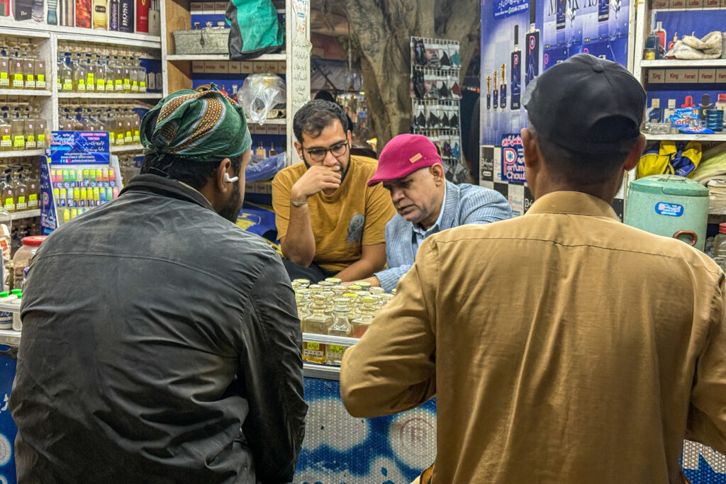 Perfumer Mursaleen Sherwani (left) and Ali Zaid interact with customers at Sherwani’s kiosk in Karachi. Credit: Aman Azhar/Inside Climate News