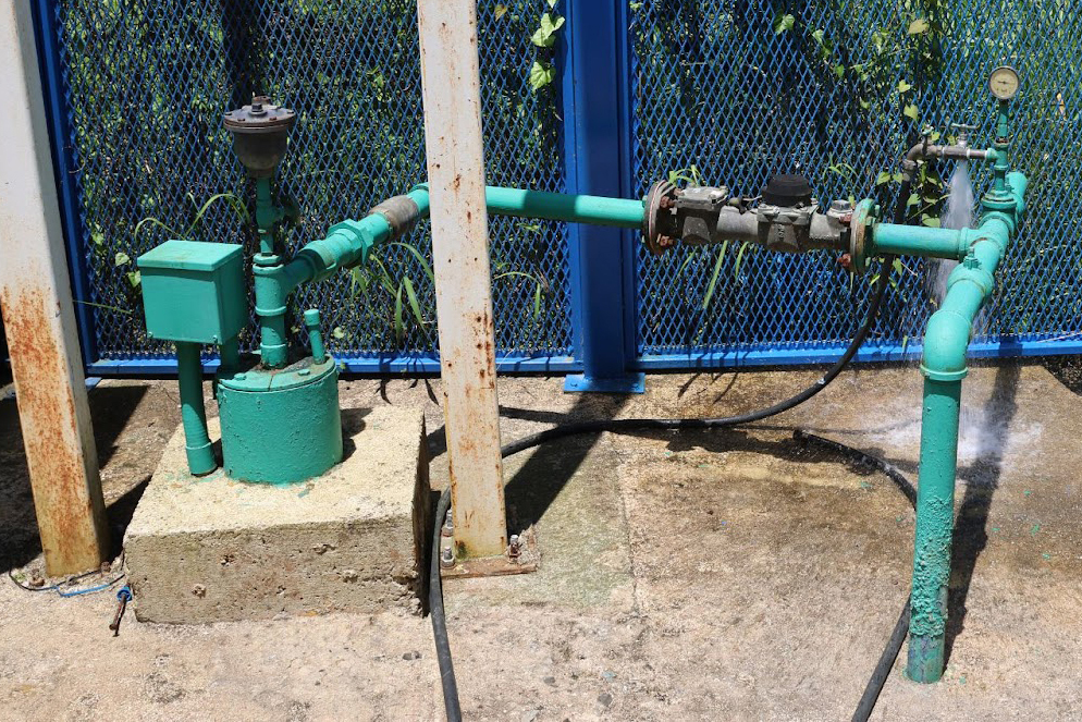 The well for the Buenos Aires Community Aqueduct in Caguas is located in a fenced-in concrete area. The water is drawn up from underground using energy from solar panels that is stored in batteries, or from a generator that serves as an alternative energy source. Credit: Sarah Mattalian