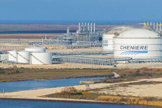An aerial view of a Cheniere Energy liquefied natural gas plant, showing white storage tanks with the company's logo