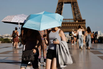 People hold umbrellas to protect themselves from the sun during a heatwave in Paris on June 30. Credit: Ludovic Marin/AFP via Getty Images
