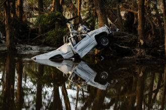 A white vehicle peeks out of the water, its reflection around it