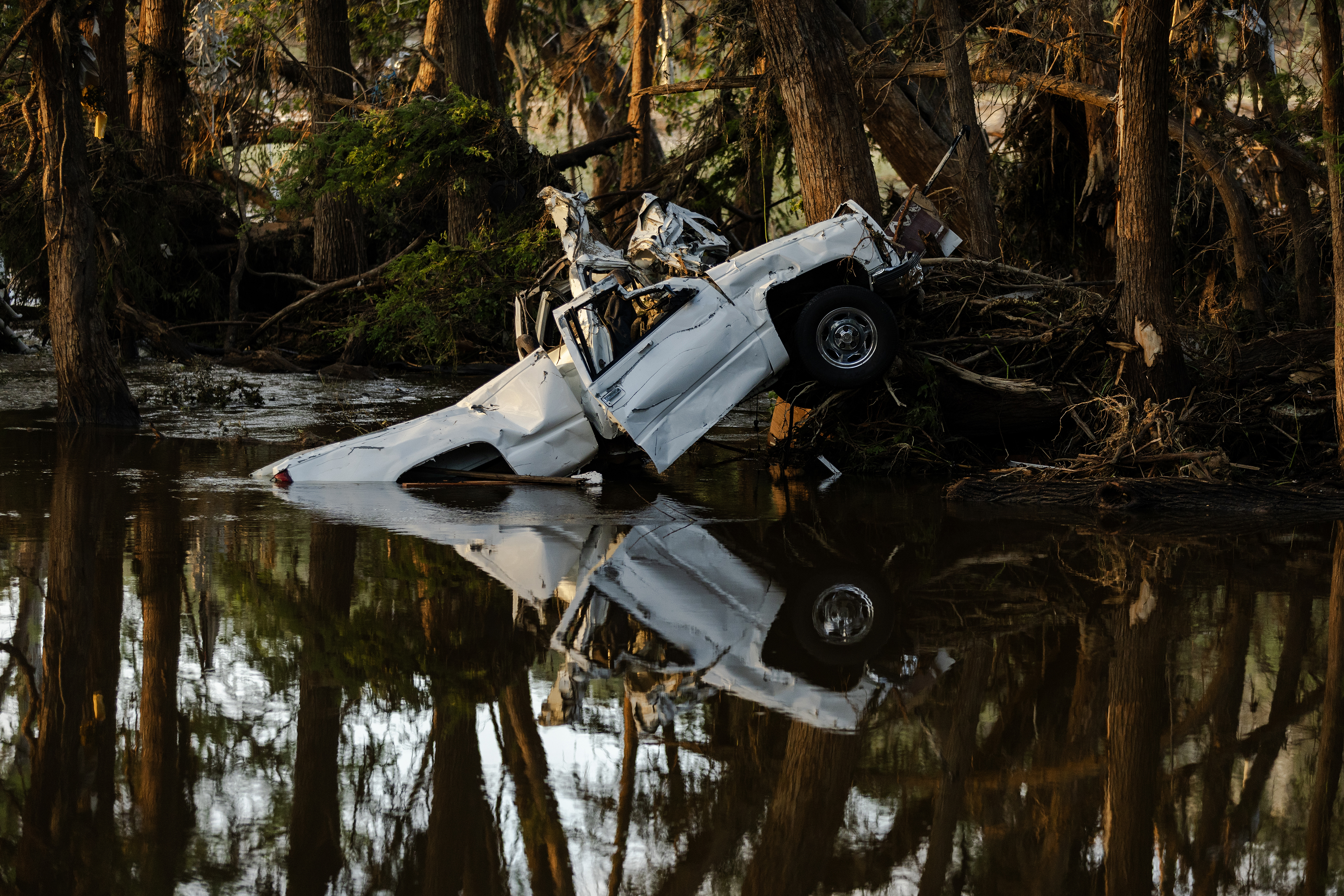 A white vehicle peeks out of the water, its reflection around it