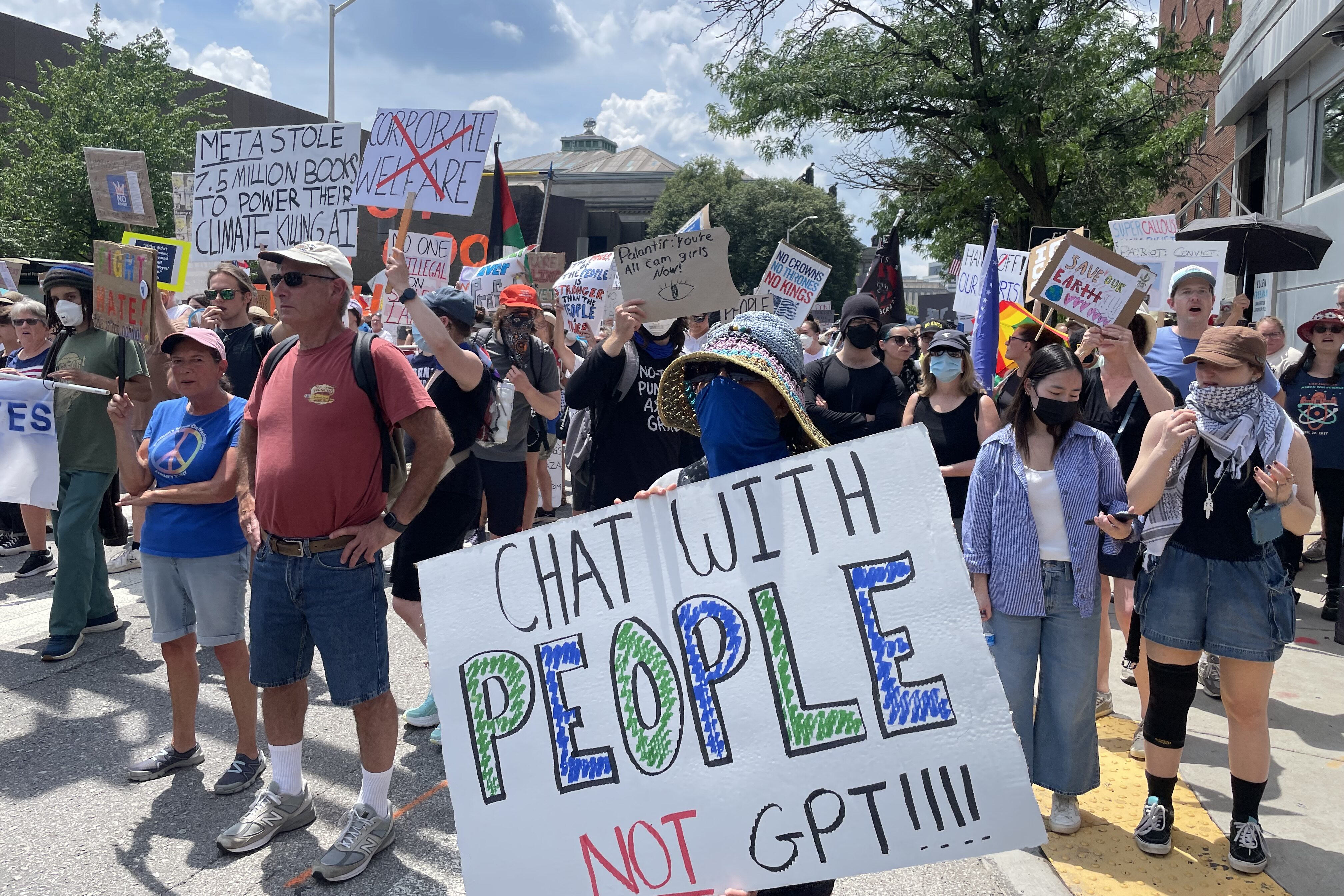 People are holding signs, one of which says, "Chat with people, not GPT!!!!"