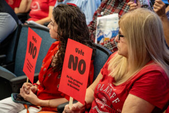 Residents dress in red to show their opposition to the proposed data center hold signs that read “Vote NO on the proposed data center in Bessemer.” Credit: Lee Hedgepeth/Inside Climate News