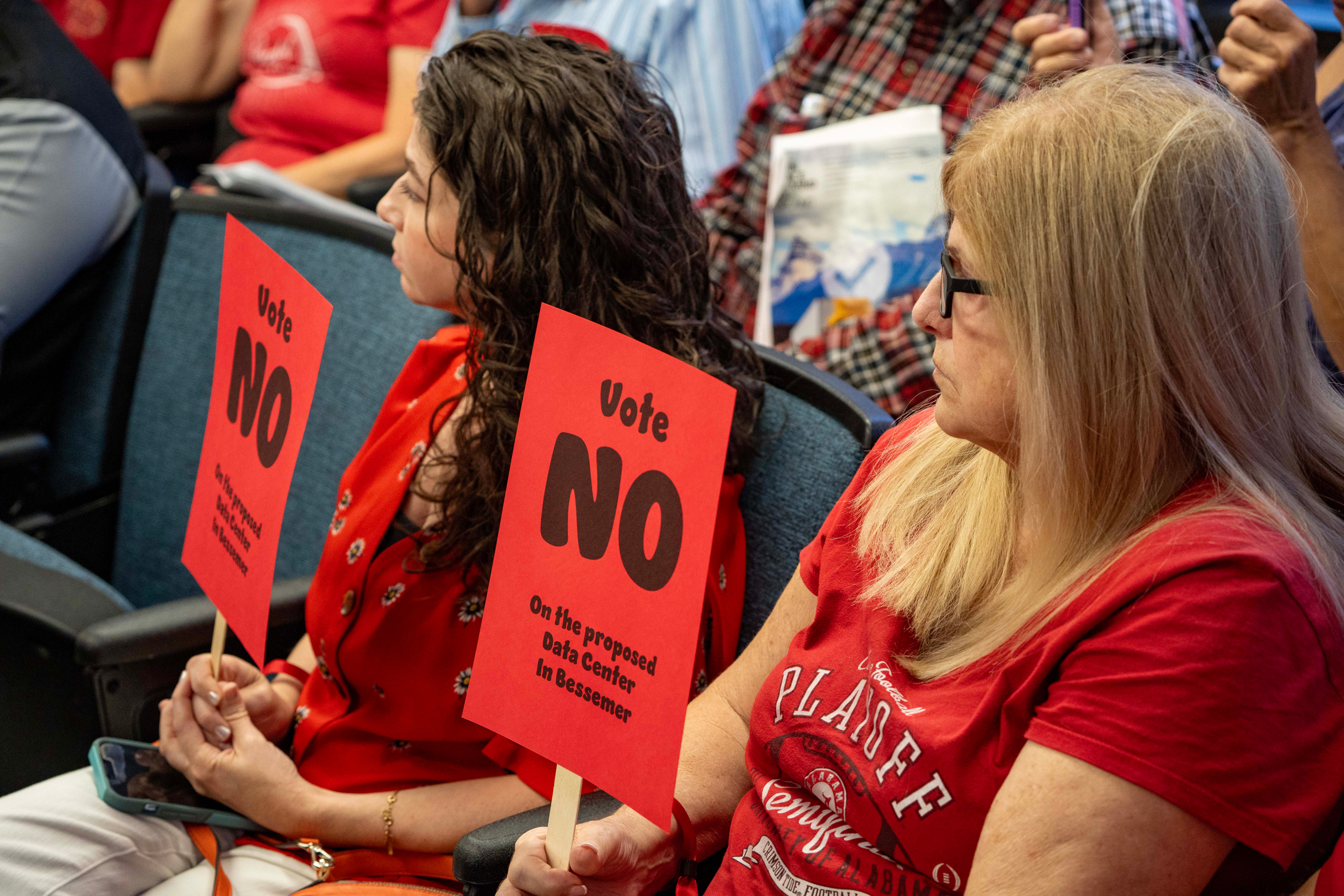 Residents dress in red to show their opposition to the proposed data center hold signs that read “Vote NO on the proposed data center in Bessemer.” Credit: Lee Hedgepeth/Inside Climate News
