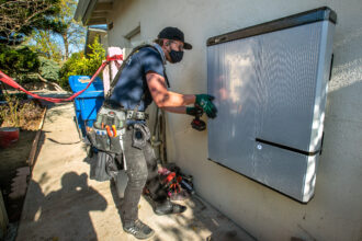 A foreman for the solar company Sunrun installs a 215-pound lithium-ion battery at a home in Granada Hills, Calif., on Jan. 4, 2020. Credit: Mel Melcon/Los Angeles Times via Getty Images