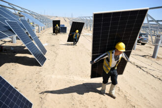Workers carry solar panels to be installed at a one-million-kilowatt photovoltaic project in Lingwu, China, on April 14. Credit: STR/AFP via Getty Images