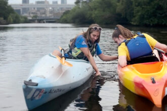 Krystyna Kurth, with the Shedd Aquarium, shows Elise Mulligan jewelweed as they kayak down the Chicago River. Credit: Leigh Giangreco/Inside Climate News