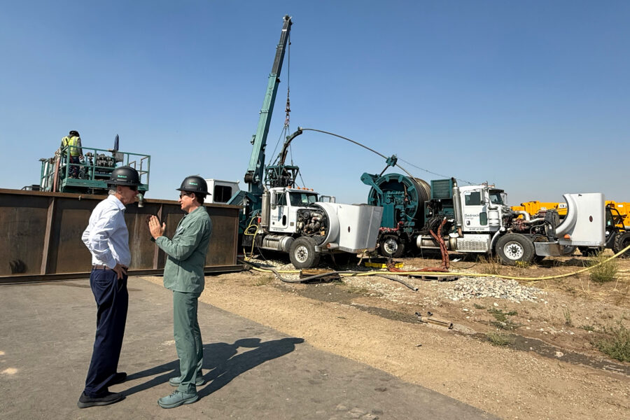 Bedrock Energy CTO Silviu Livescu (right) and Sen. John Hickenlooper (D-Colo.) talk in front of a drill rig on Wednesday at the Northwest Colorado Business District in Hayden, Colo. Credit: Emily Goldfield