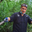 With machete in hand, Isiah Cruz clears a patch of invasive common reed along the Passaic River’s edge. Credit: Anna Mattson/Inside Climate News