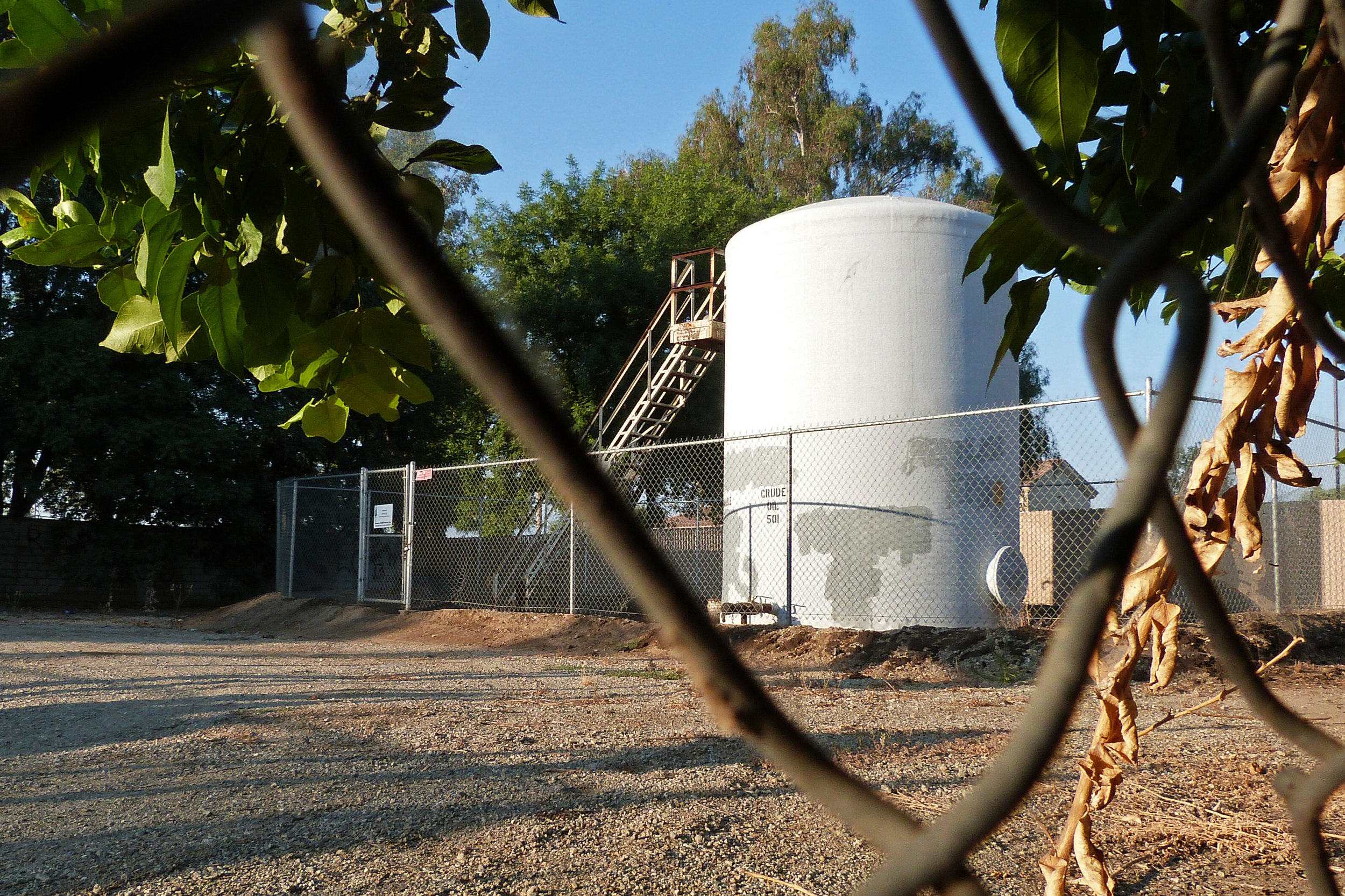 Hydrocarbon storage tanks—like this one in the backyard of a home in Arvin, Calif., and next to a playground—pose a disproportionate health risk when they leak. In addition to the climate super-pollutant methane, they emit a cocktail of toxic gases, including the carcinogen benzene. Credit: Liza Gross/Inside Climate News