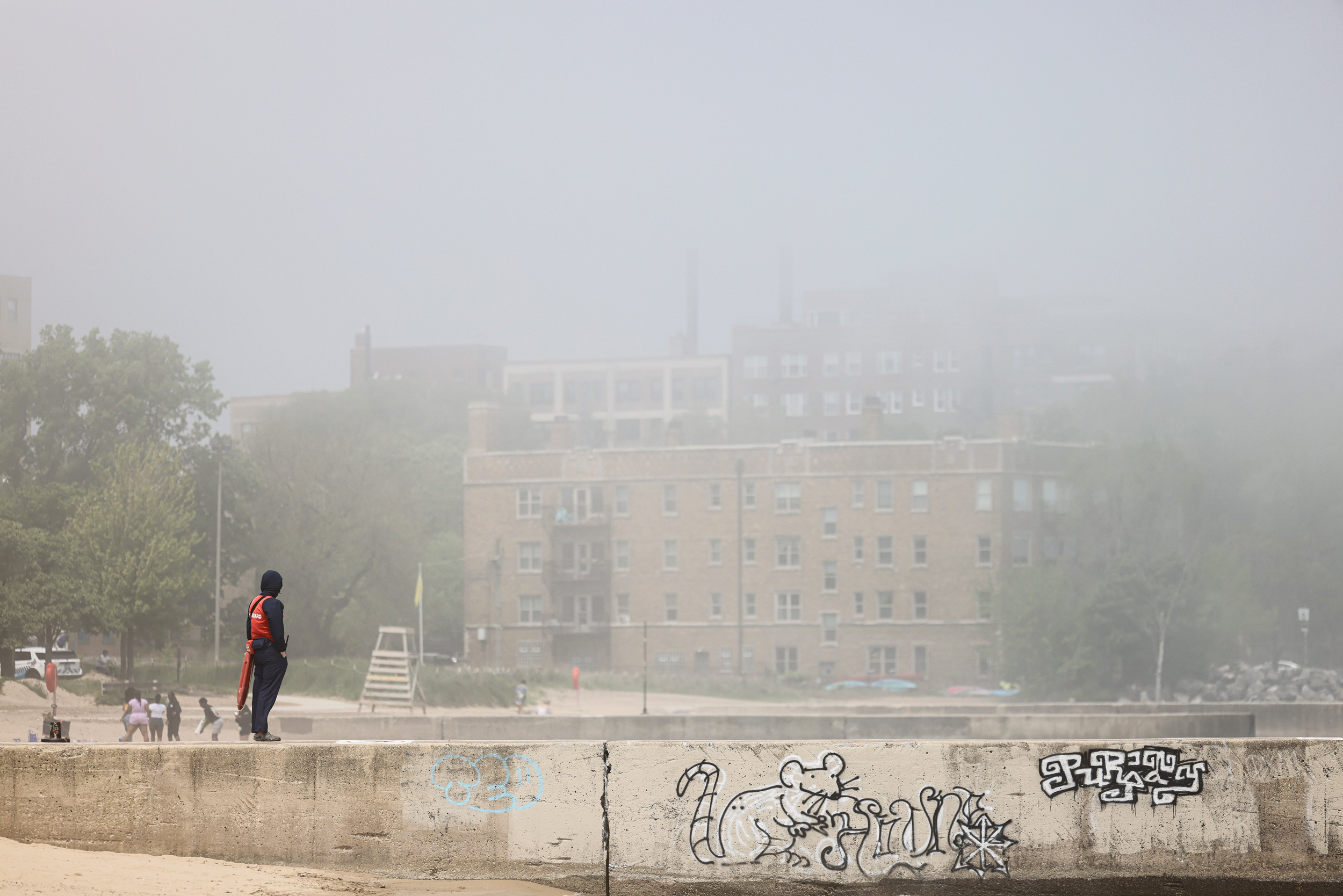 A lifeguard stands watch amid a haze of Canadian wildfire smoke at Loyola Beach on Chicago’s North Side in June. The West and South sides of the city get heavy air pollution all year. Credit: Anthony Vazquez/Sun-Times