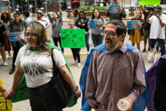 Samuel Corona (right), an activist with the Alliance of the Southeast, chants, “Stop General Iron” outside Chicago’s City Hall. The U.S. Department of Housing and Urban Development says it will no longer monitor a civil rights agreement with Chicago over the controversial scrap metal operation. Credit: Pat Nabong/Sun-Times