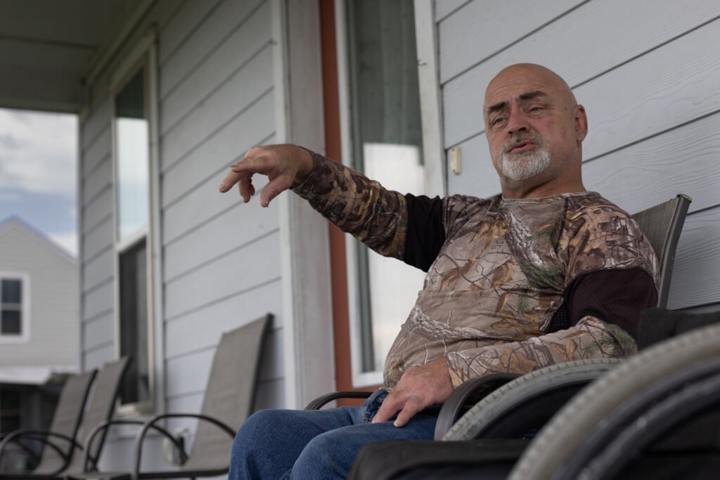 “I never expected that relocation was going to happen in my lifetime. Now that I see that it has happened, it’s not a celebration,” says Chris Brunet, pictured here in front of his house in the Louisiana Isle De Jean Charles resettlement, known as “The New Isle.” Brunet was one of the 37 people or families in the first fully federally-funded relocation project in the country. Credit: Jeffrey Basinger/Floodlight