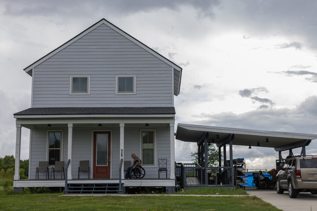 “I never expected that relocation was going to happen in my lifetime. Now that I see that it has happened, it’s not a celebration,” says Chris Brunet, pictured here in front of his house in the Louisiana Isle De Jean Charles resettlement, known as “The New Isle.” Brunet was one of the 37 people or families in the first fully federally-funded relocation project in the country. Credit: Jeffrey Basinger/Floodlight