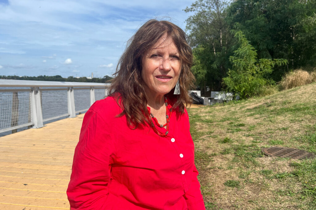 Cynthia Mellon, the playwright of “Flow(ish),” sits next to the Passaic River. Credit: Anna Mattson/Inside Climate News