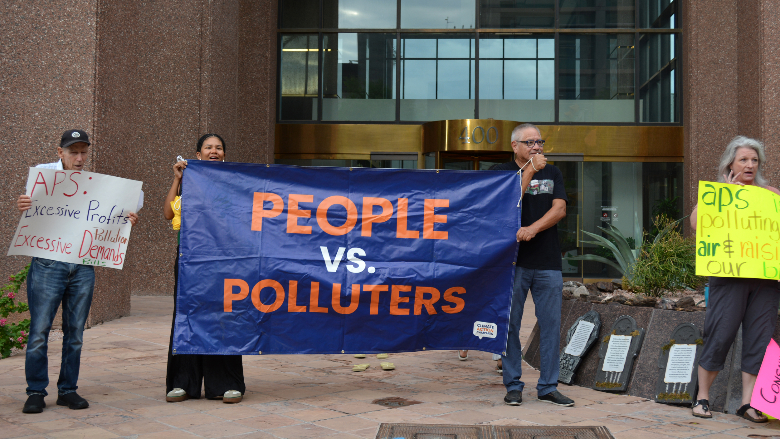 Protesters stand outside of Arizona Power Service’s headquarters on Thursday after the utility’s recent decision to walk back its clean energy goals. Credit: Wyatt Myskow/Inside Climate News