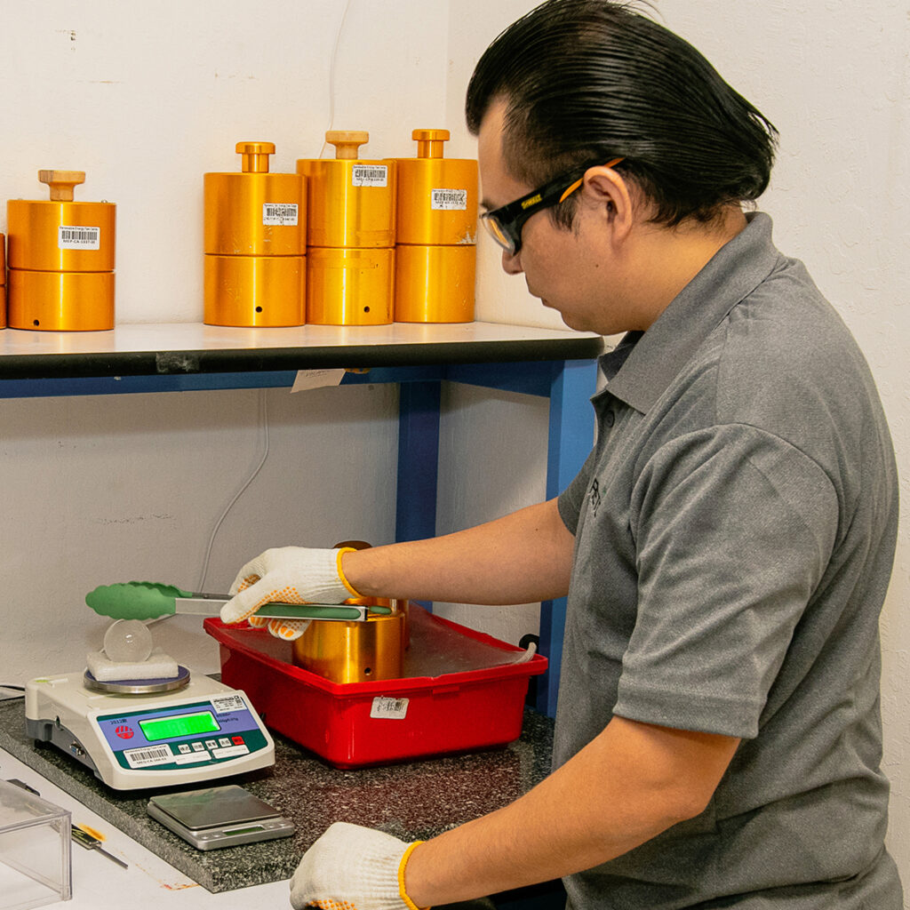 An employee at the Renewable Energy Test Center weighs an ice ball that is meant to simulate a hailstone. Credit: RETC