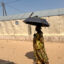 A fishing vendor uses an umbrella to protect herself from the midday sun during a heat wave in St. Louis, Senegal. Credit: Lucia Weiß/picture alliance via Getty Images