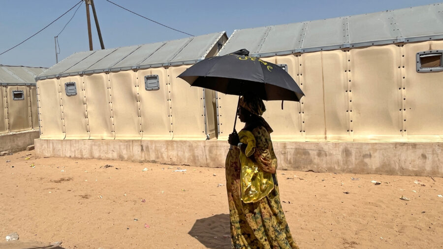 A fishing vendor uses an umbrella to protect herself from the midday sun during a heat wave in St. Louis, Senegal. Credit: Lucia Weiß/picture alliance via Getty Images