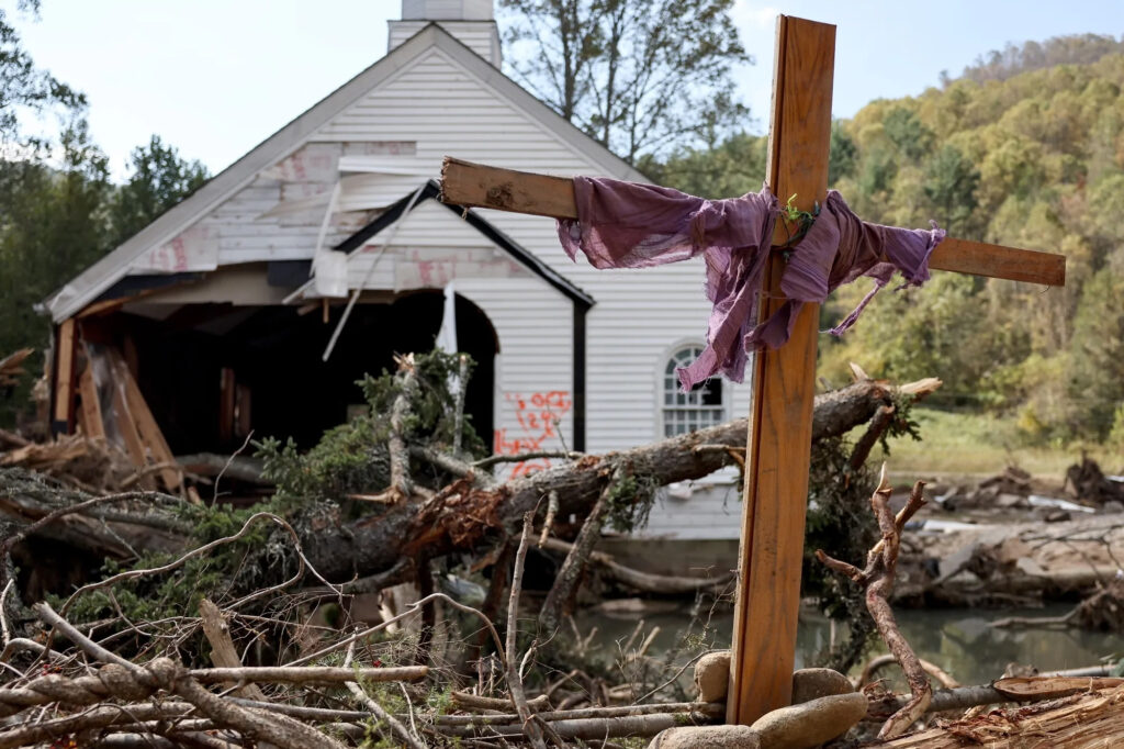 A makeshift cross stands amid fallen trees in front of church destroyed by Hurricane Helene in Swannanoa, N.C., as seen on Oct. 6, 2024. Credit: Mario Tama/Getty Images via Grist