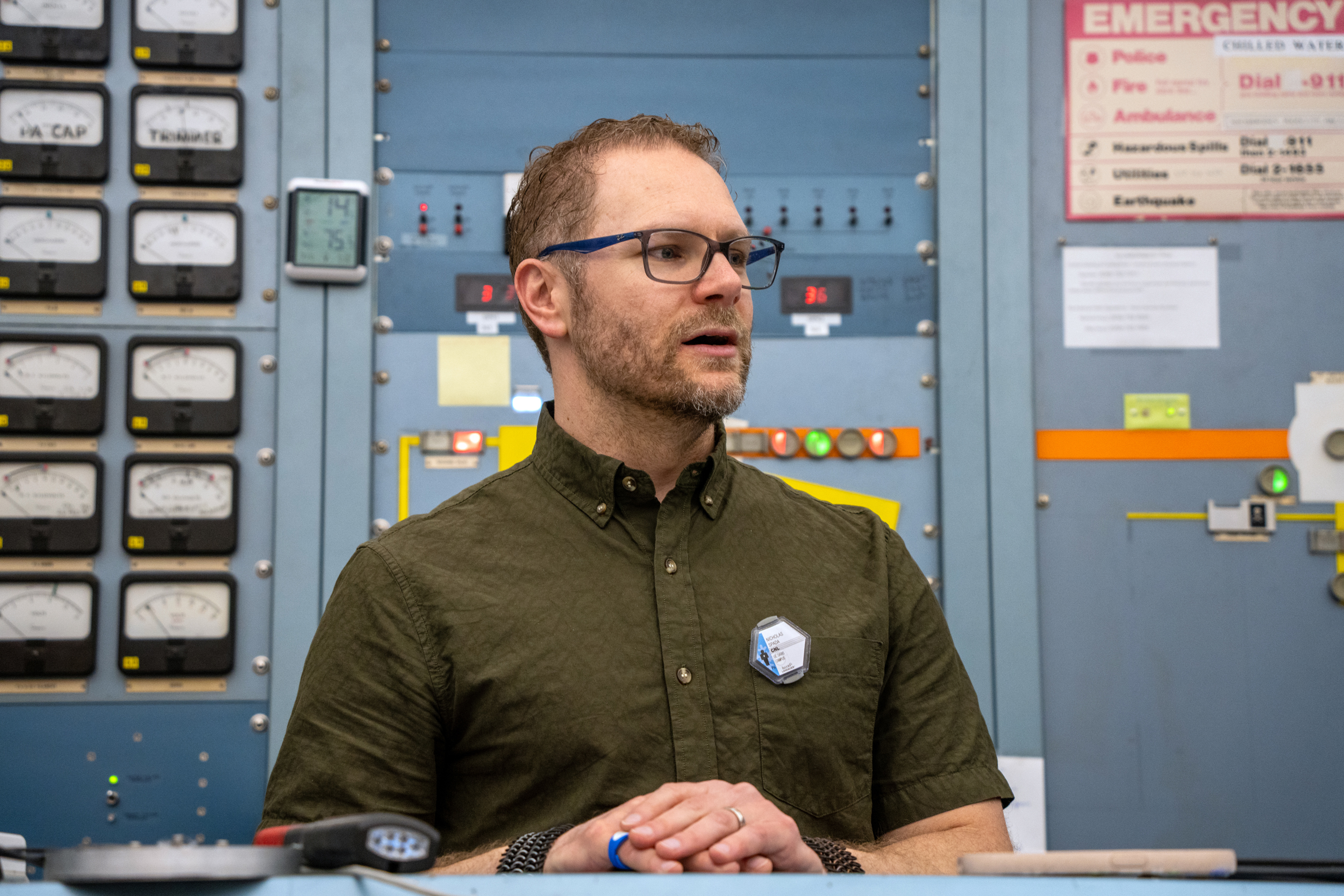 Nicholas Spada stands in front of an instument panel at UC Davis’ Crocker Nuclear Laboratory with a radiation exposure monitor prominently pinned to his shirt’s pocket on March 25.