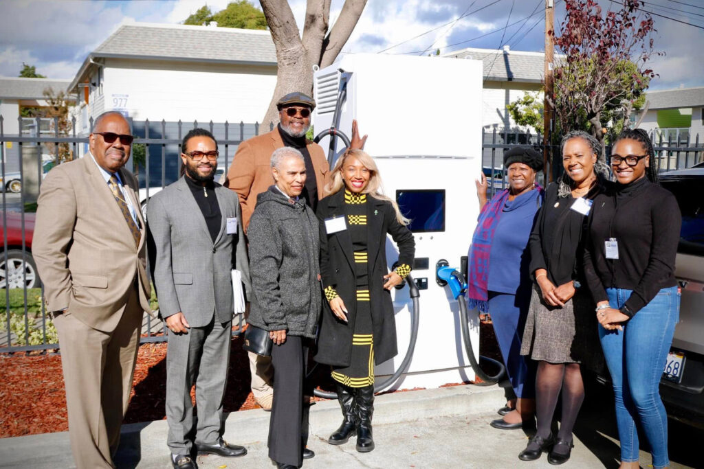 Members of Glad Tidings and Green the Church stand next to an EV charging station at the Community Decarbonization Hub. Credit: Courtesy of Green the Church