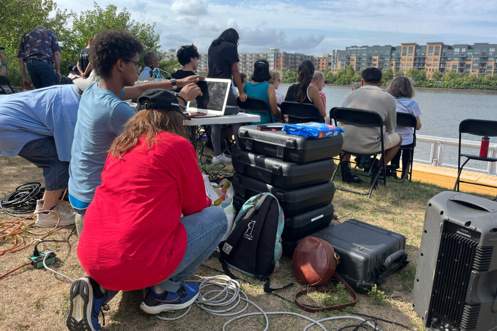 Before the show begins, playwright Cynthia Mellon tests the microphones at the outdoor sound booth along the Passaic River. Credit: Anna Mattson/Inside Climate News