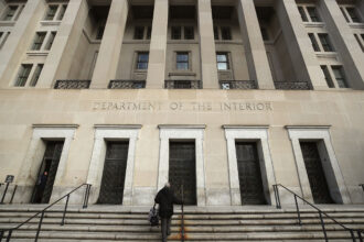 The Interior Department headquarters is shown from an angle with a person walking up the steps