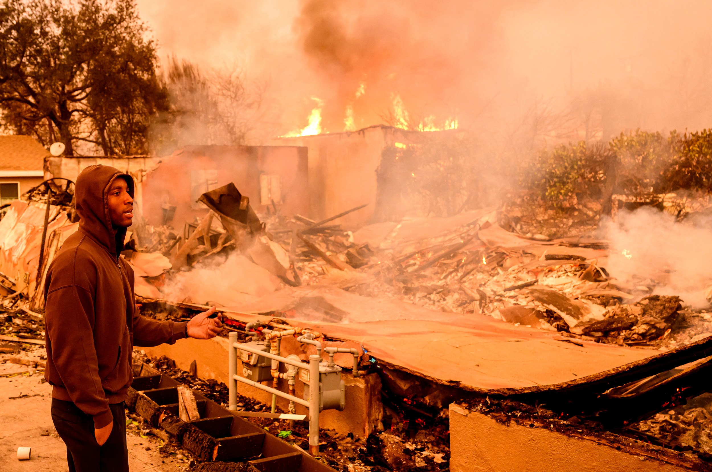 A man views his property as it burns during the Eaton Fire in the Altadena area of Los Angeles County on Jan. 8. Credit: Josh Edelson/AFP via Getty Images
