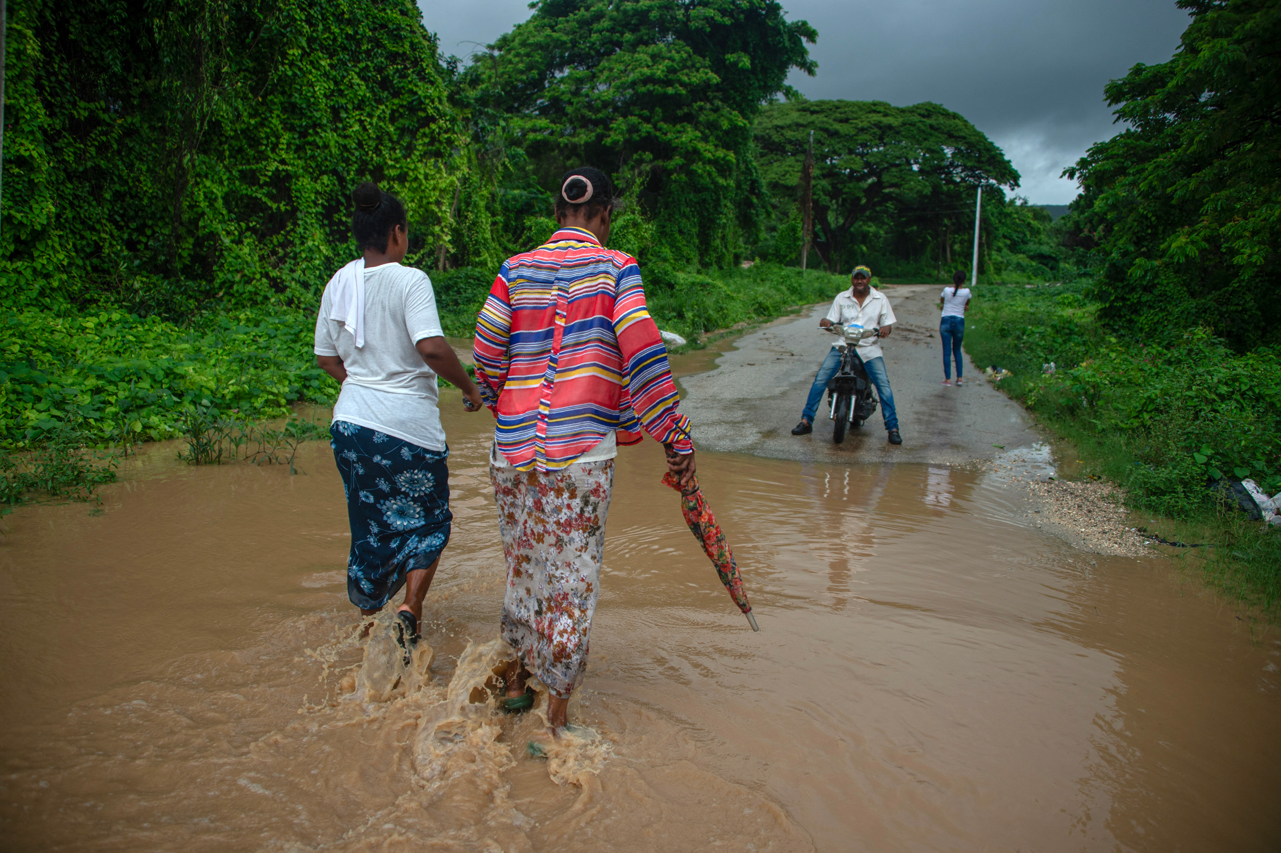 Women walk through flooded waters after the passing of Melissa on Tuesday in Barahona, Dominican Republic. Credit: Carlos Fabal/AFP via Getty Images