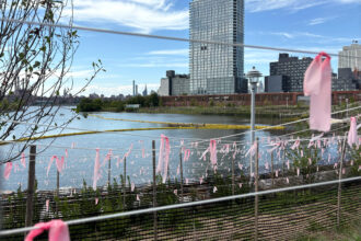 A view from a new area of Brooklyn’s Bushwick Inlet Park. Across the inlet, the brown MTA facility marks where property firm Gotham Organization wants to build apartments. Credit: Lauren Dalban/Inside Climate News