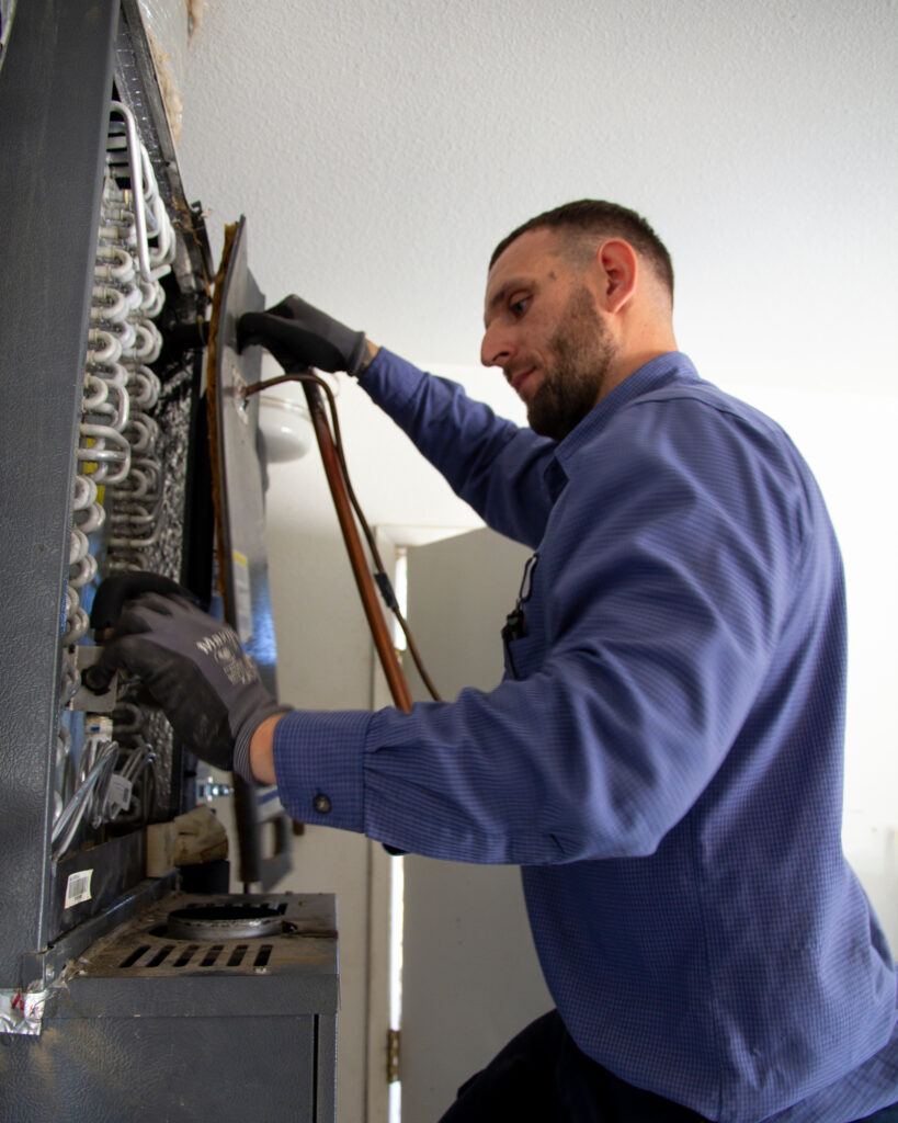 A technician from John Harrison Contracting removes a gas-powered HVAC system before installing a heat pump for Vasquez’s home. Credit: Twilight Greenaway/Inside Climate News