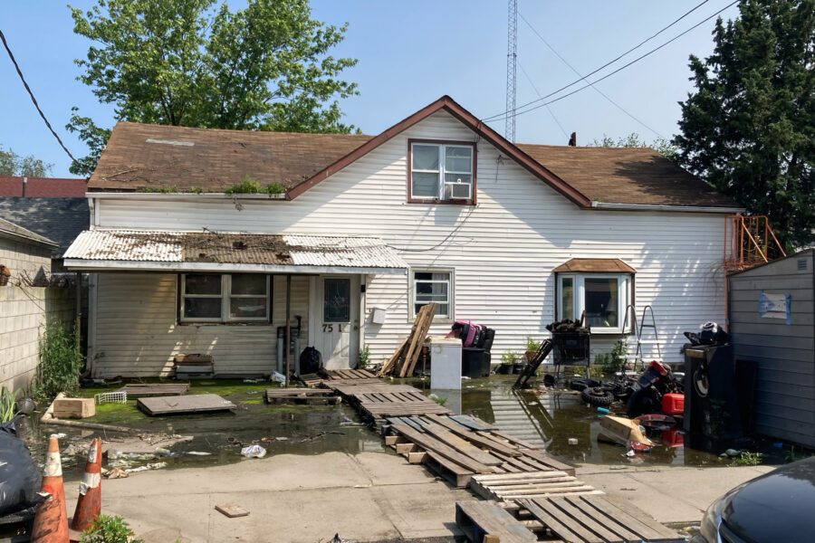 Water pools in the front yard of a house in “The Hole” of New York City. A makeshift bridge has been constructed out of wooden planks. Credit: Lauren Dalban/Inside Climate News